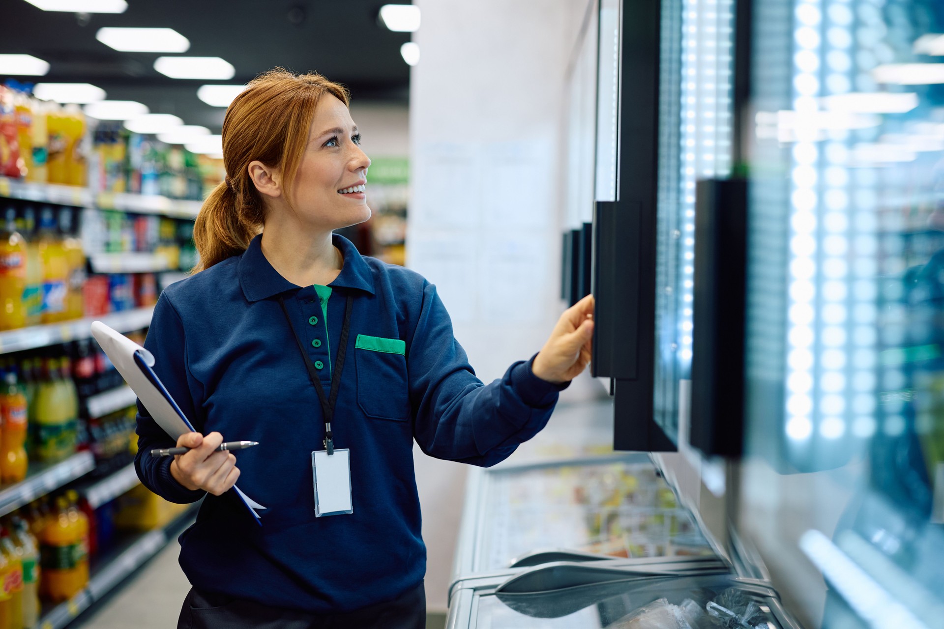 Happy store manager inspecting food in refrigerated compartment at supermarket.